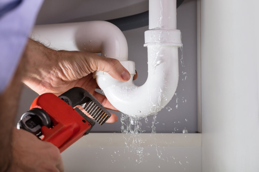 plumber fixing a leaky pipe